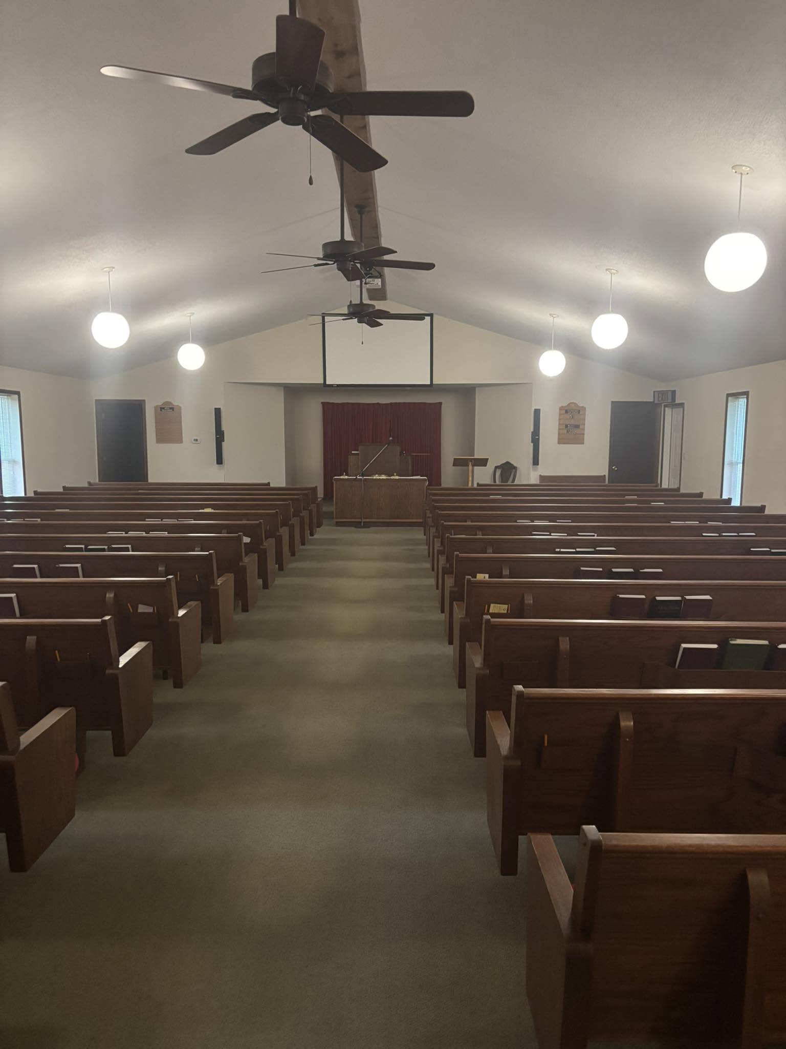 The sanctuary — oak pews, pulpit, and red curtain